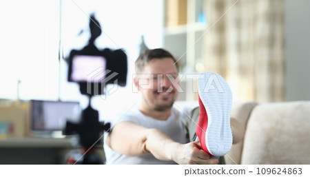 Cheerful male blogger calls red sneakers while recording new video for blog 109624863