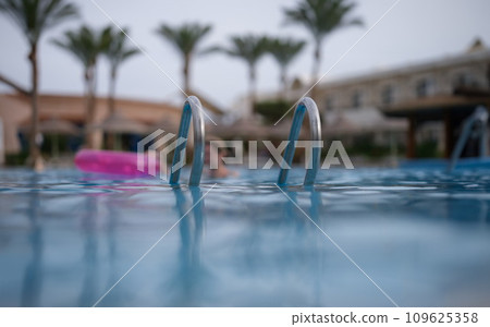 Wet metal handrails on surface of pool closeup Wet metal handrails on surface of pool closeup 109625358