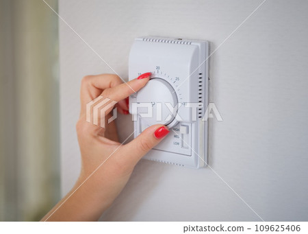 Female hand adjusting temperature of air conditioner with roller closeup Female hand adjusting temperature of air conditioner with roller closeup 109625406