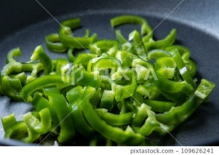 A cooking scene of frying green peppers in a frying pan. A cooking scene of frying green peppers in a frying pan. 109626241