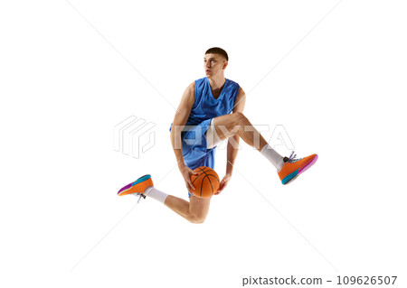 Dynamic image of young man, basketball player in motion, jumping with ball, scoring winning goal isolated over white background. Sport concept 109626507