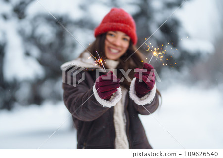 Stylish woman with bengal light in hand enjoying and have fan winter holidays among snowy landscape. 109626540