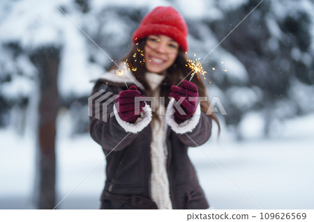 Stylish woman with bengal light in hand enjoying and have fan winter holidays among snowy landscape. Stylish woman with bengal light in hand enjoying and have fan winter holidays among snowy landscape. 109626569