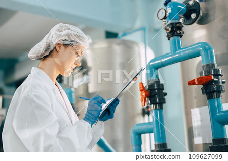 Drinking water factory purification process. Hygiene factory worker female monitor checking valve and water pipe production flow control. 109627099