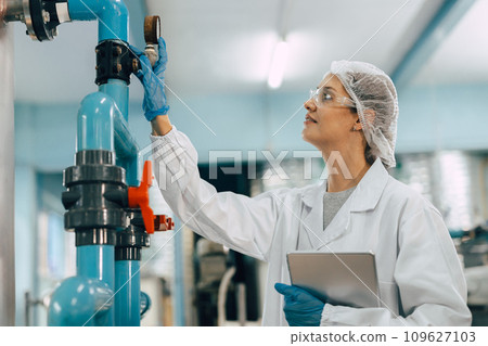 Drinking water factory purification process. Hygiene factory worker female monitor checking valve and water pipe production flow control. Drinking water factory purification process. Hygiene factory worker female monitor checking valve and water pipe production flow control. 109627103