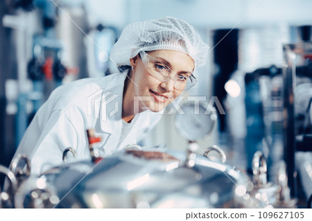 Women worker in drinking water plant clean hygiene uniform monitor control pressure gauge water purity process. 109627105