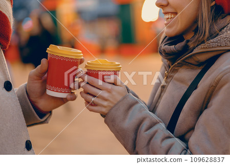 Couple sharing a joyful moment with hot drinks in festive cups at a Christmas market 109628837