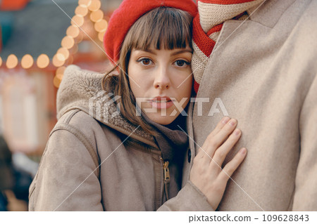 Young woman finding comfort in her partner's embrace at a festive outdoor Christmas market Young woman finding comfort in her partner's embrace at a festive outdoor Christmas market 109628843