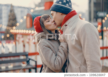 Romantic couple kissing gently at a festive outdoor Christmas market Romantic couple kissing gently at a festive outdoor Christmas market 109628847