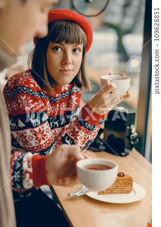 Thoughtful young lady in a Christmas jumper savoring tea at a quaint cafe 109628851