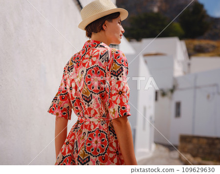 Nice asian Happy Female in boho dress Enjoying Sunny Day on Greek Islands. Travel to Lindos, Mediterranean islands outside tourist season. Tourist woman on vacation in Greece walking through the Nice asian Happy Female in boho dress Enjoying Sunny Day on Greek Islands. Travel to Lindos, Mediterranean islands outside tourist season. Tourist woman on vacation in Greece walking through the 109629630