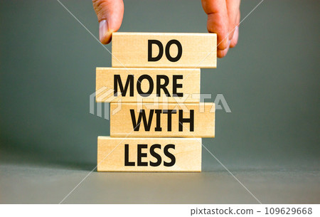 Do more with less symbol. Concept word Do more with less on beautiful wooden block. Beautiful grey table grey background. Businessman hand. Business do more with less concept. Copy space. 109629668
