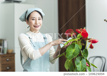 一個穿著圍裙的女人正在照顧室內植物 109629894