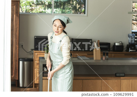 A woman in an apron cleaning the floor 109629991