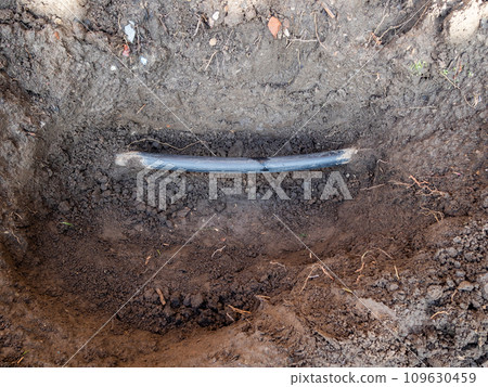plastic water pipe damaged by shovel in ground 109630459