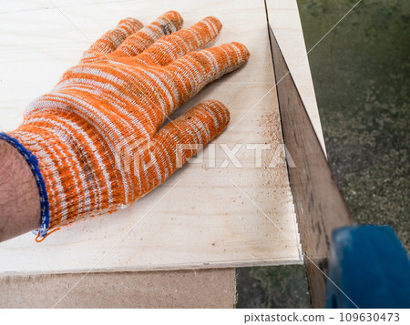 POV view of carpenter sawing plywood with hacksaw POV view of carpenter sawing plywood with hacksaw 109630473