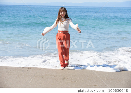一個女人赤腳走在沙灘上 109630648
