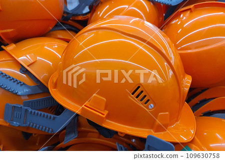 An orange work helmet lies among other similar helmets of general workers.. Construction safety worker equipment An orange work helmet lies among other similar helmets of general workers.. Construction safety worker equipment 109630758