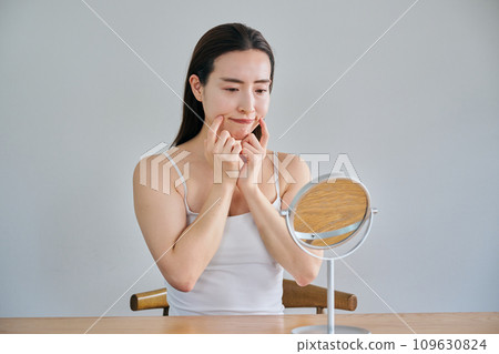 30多歲的女性在照鏡子時擔心自己皮膚上有皺紋 109630824