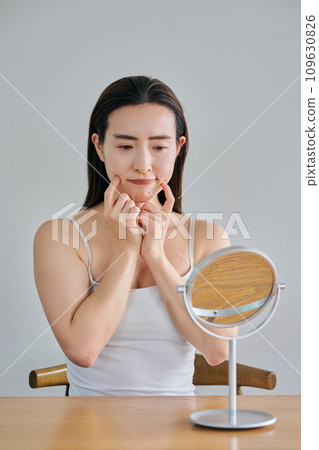 30多歲的女性在照鏡子時擔心自己皮膚上有皺紋 109630826
