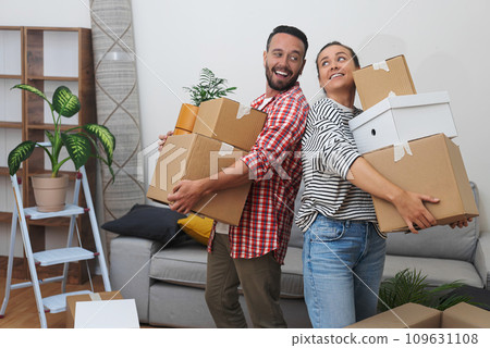 New Tenant Life: Young couple tenants, with a stack of cardboard relocation boxes, stand in their new apartment's living room New Tenant Life: Young couple tenants, with a stack of cardboard relocation boxes, stand in their new apartment's living room 109631108