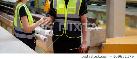Young caucasian engineer man and woman hold blueprint meeting and checking electric train. Young caucasian engineer man and woman hold blueprint meeting and checking electric train. 109631179