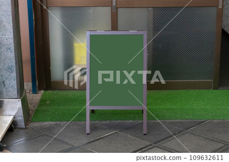 Blank white outdoor advertising stand/sandwich board mock up template. Clear street signage board placed by an outdoor dinning area of a restaurant. Background texture of standee on street. 109632611