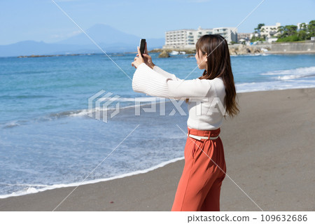 A woman taking pictures of the sea with a smartphone A woman taking pictures of the sea with a smartphone 109632686