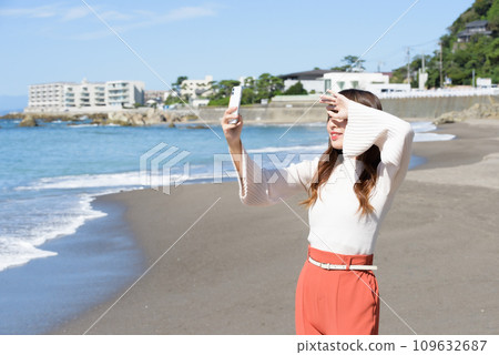 A woman taking pictures of the sea with a smartphone 109632687