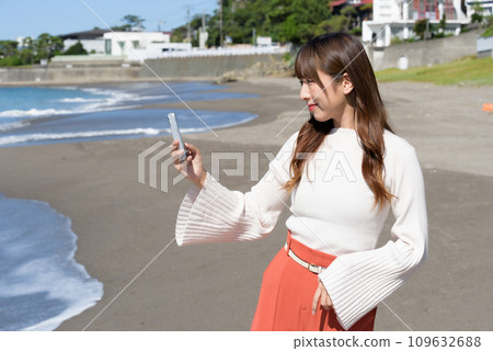 A woman taking pictures of the sea with a smartphone A woman taking pictures of the sea with a smartphone 109632688