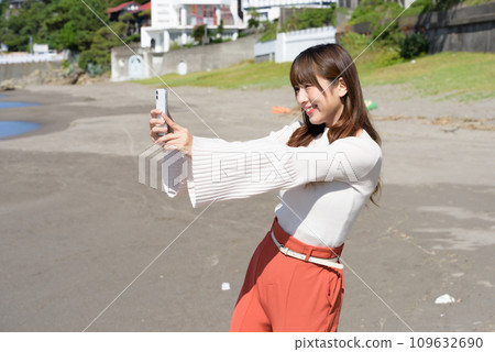 一位女士用智慧型手機拍攝大海的照片 109632690