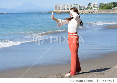 A woman taking pictures of the sea with a smartphone 109632691
