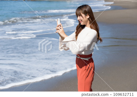 A woman taking pictures of the sea with a smartphone 109632711