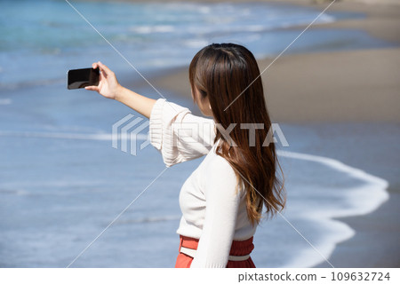 A woman taking pictures of the sea with a smartphone A woman taking pictures of the sea with a smartphone 109632724