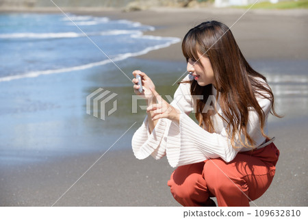 一位女士用智慧型手機拍攝大海的照片 109632810