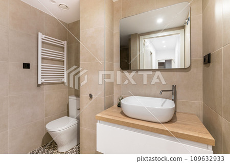Sink with tap and mirror over chest of drawers in bathroom 109632933