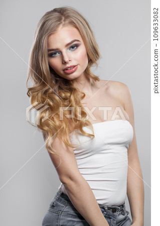 Attractive young blonde model with long wavy hair, makeup and clean skin on white background. Attractive young blonde model with long wavy hair, makeup and clean skin on white background. 109633082