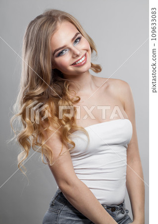 Happy young blonde model with long wavy hair, makeup and clean skin on white background. Happy young blonde model with long wavy hair, makeup and clean skin on white background. 109633083