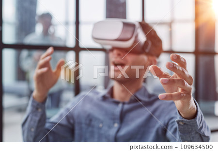 Cool handsome man put on virtual reality goggles for the first time in the office. Cool handsome man put on virtual reality goggles for the first time in the office. 109634500