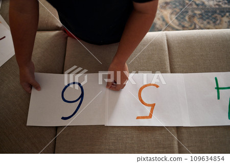 Children's hands arrange numbers in order on the sofa. Close-up. 109634854