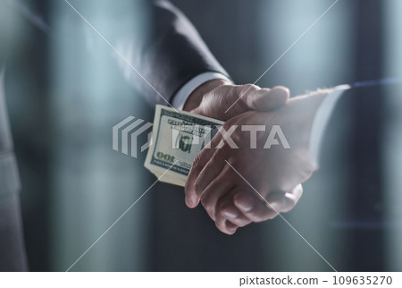 Handshake with the transfer of money on a black background 109635270
