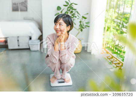 A woman in her 20s weighing herself 109635720