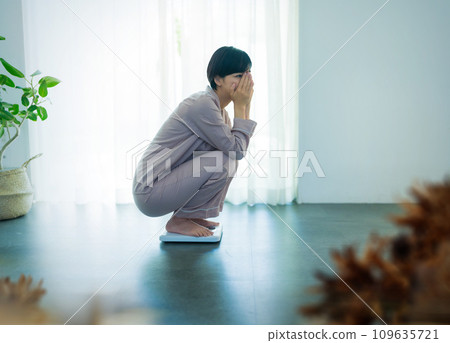A woman in her 20s weighing herself 109635721