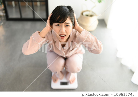 A woman in her 20s weighing herself 109635743