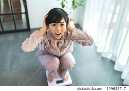 A woman in her 20s weighing herself A woman in her 20s weighing herself 109635747