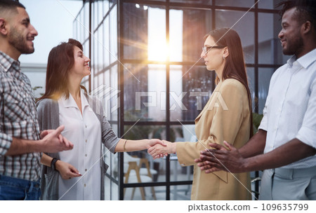Two professional business people shaking hands in an office lobby 109635799