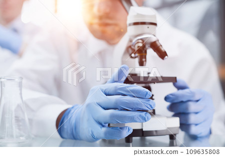 Young scientist looking through a microscope in a laboratory. Young scientist doing some research. 109635808
