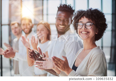Group of businesspeople sitting in a line and applauding. 109635832