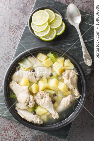 Chicken souse is a Bahamian soup that is a clear broth where the meat and the vegetables are boiled down in the juice of fresh citrus closeup on the plate. Vertical top view Chicken souse is a Bahamian soup that is a clear broth where the meat and the vegetables are boiled down in the juice of fresh citrus closeup on the plate. Vertical top view 109636008