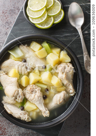 Bahamian chicken souse is a poultry dish made with chicken wings, onions, potatoes, celery, lime juice, allspice closeup on the plate on the table. Vertical top view Bahamian chicken souse is a poultry dish made with chicken wings, onions, potatoes, celery, lime juice, allspice closeup on the plate on the table. Vertical top view 109636009